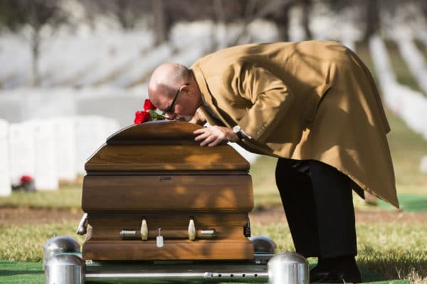 Man kissing casket - What is a graveside service?