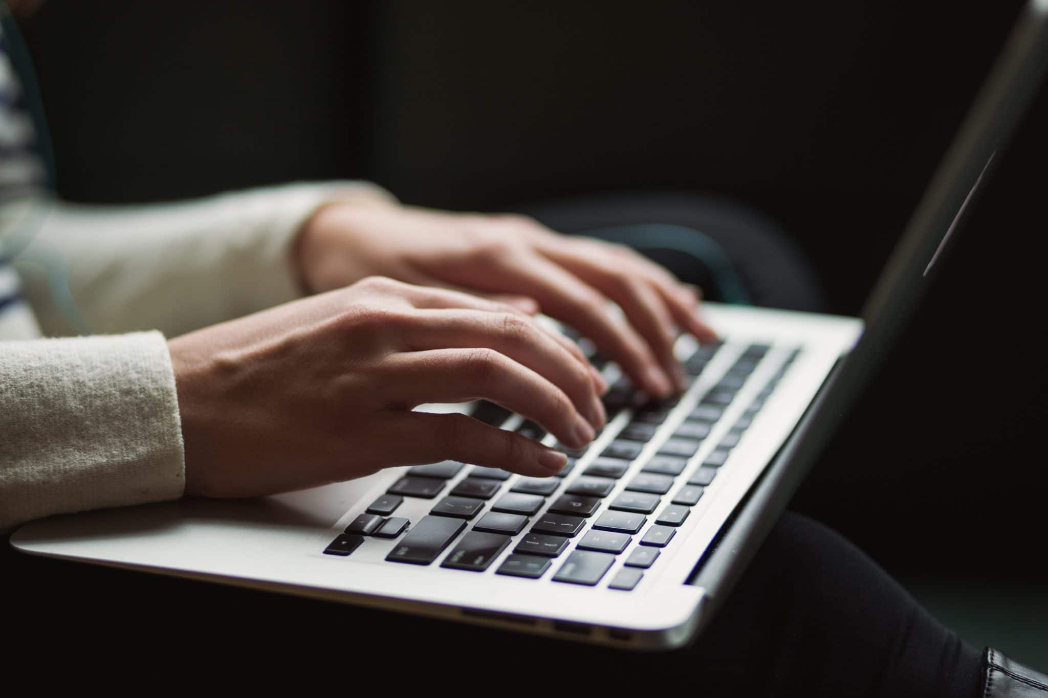 person typing on laptop - online memorial website