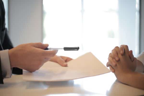 Funeral Bond vs Funeral Insurance - person handing document and pen across a table