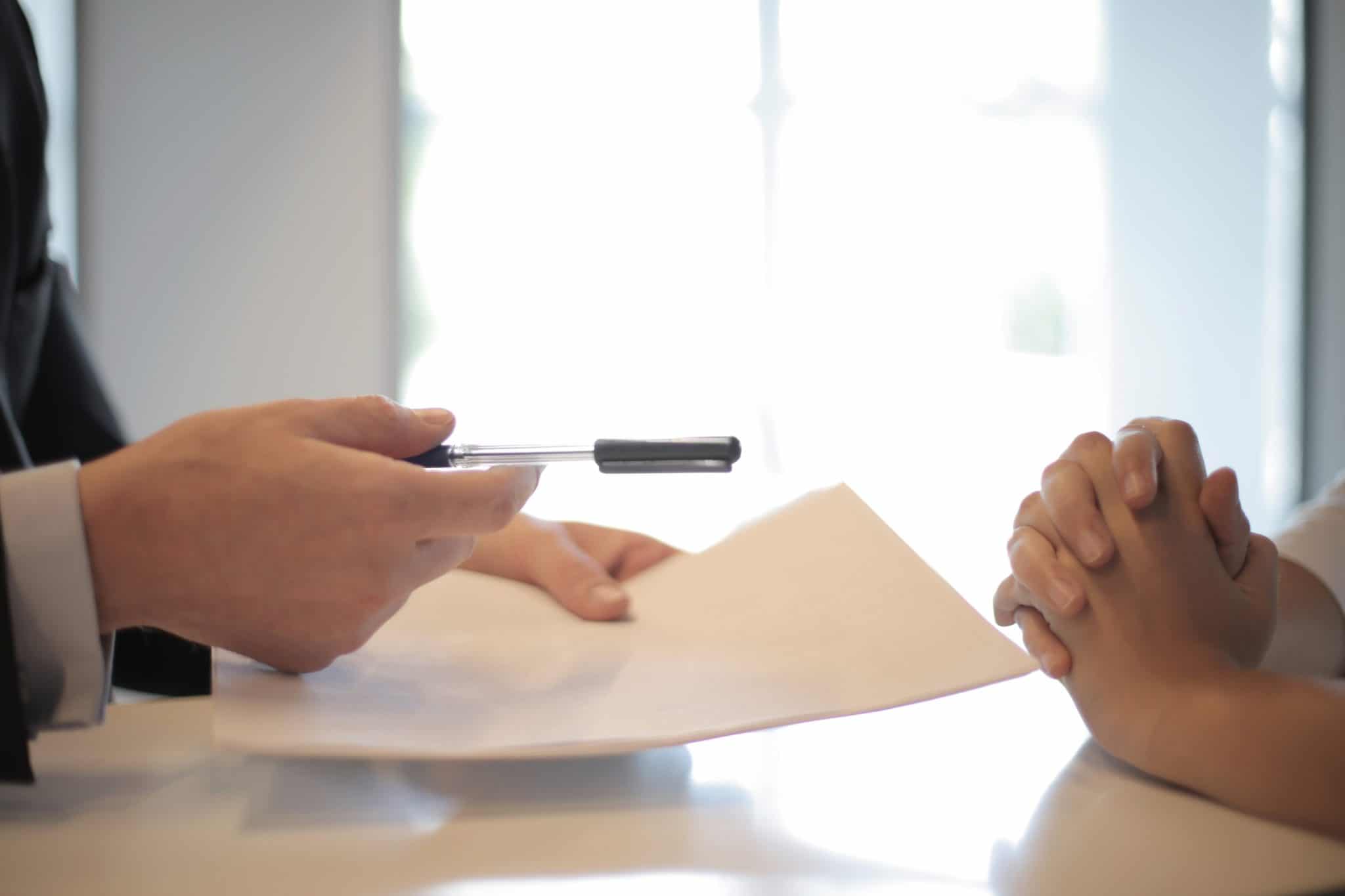 Funeral Bond vs Funeral Insurance - person handing document and pen across a table